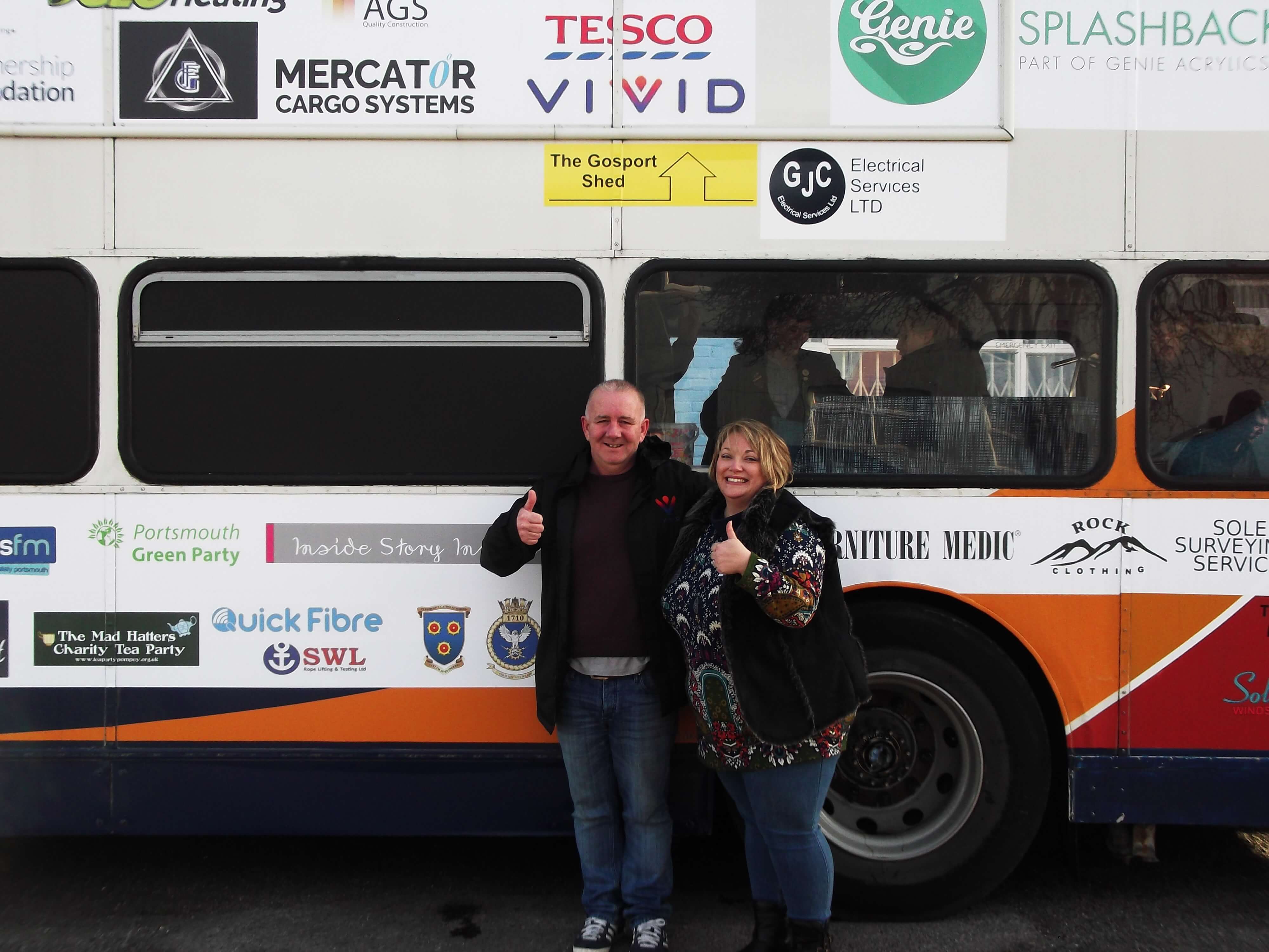man and woman stood next to bus smiling