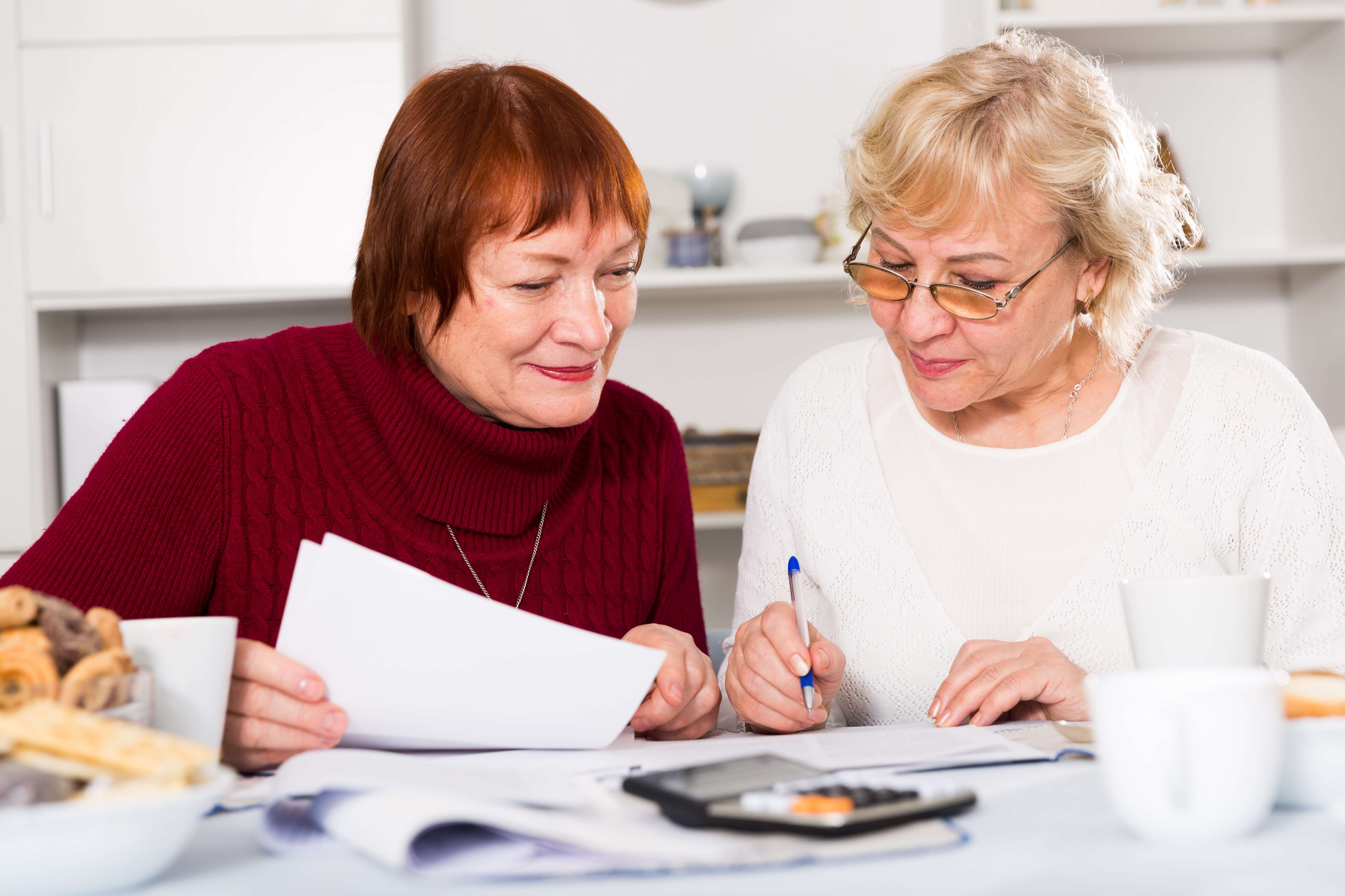 2 older women sat down looking at papers